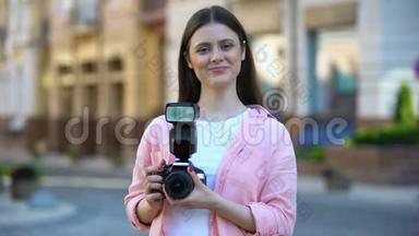 微笑的年轻女子站在城市街道上，带着相机上<strong>摄影课</strong>